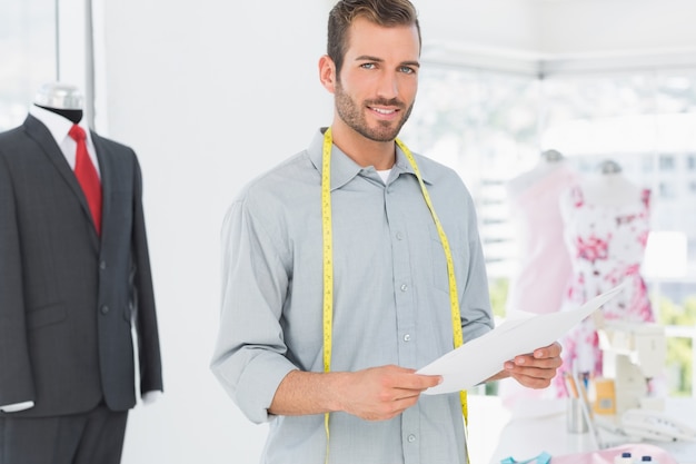 Créateur de mode masculine tenant des croquis dans le studio