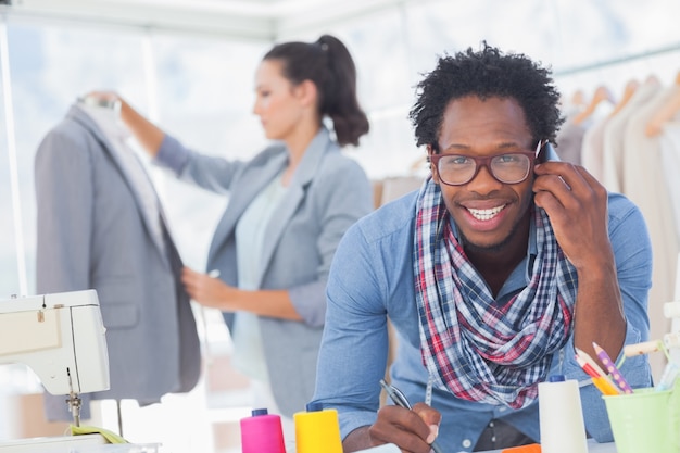 Photo créateur de mode souriant au téléphone