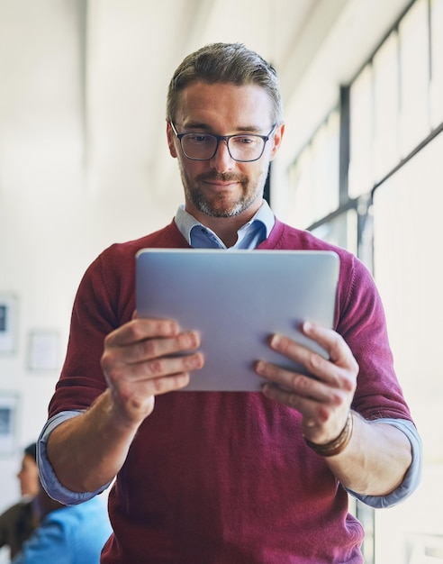 Créatif et homme d'affaires de tablette dans un bureau pour une organisation de conception de médias sociaux ou un consultant Engagement de contenu Publication et production de diffusion avec une personne pour la gestion numérique ou la recherche
