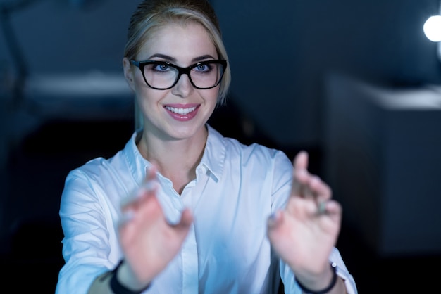 Création d'un nouveau langage de programmation. Femme informatique expérimentée et talentueuse positive assise au bureau et utilisant les technologies futures tout en travaillant sur le projet