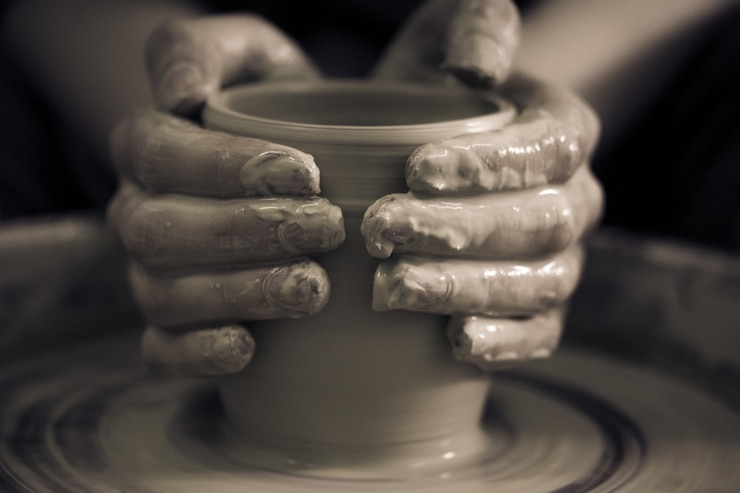 Photo création de produits en céramique en gros plan d'argile blanche. le sculpteur en atelier fait un gros plan de cruche en argile. maître cruche. tour de potier tordu. art, créativité. les traditions culturelles. fait main. artisanat.