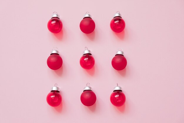 Creative Christmas plat poser composition avec des boules de verre rouge sur fond rose. Vue de dessus