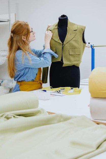 Une créatrice de mode ou une couturière essaie une veste sur un mannequin.