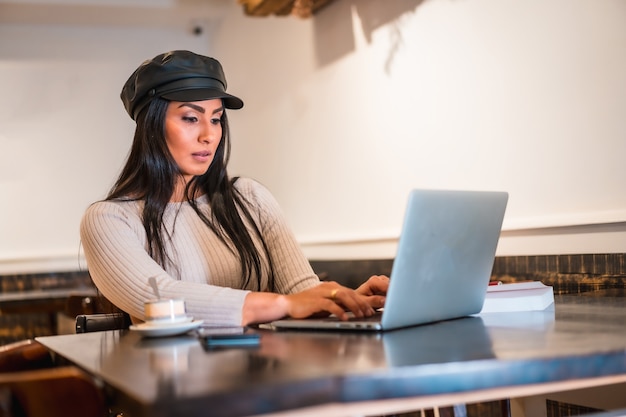 Créatrice de mode latine faisant des dessins dans une cafétéria avec son ordinateur portable