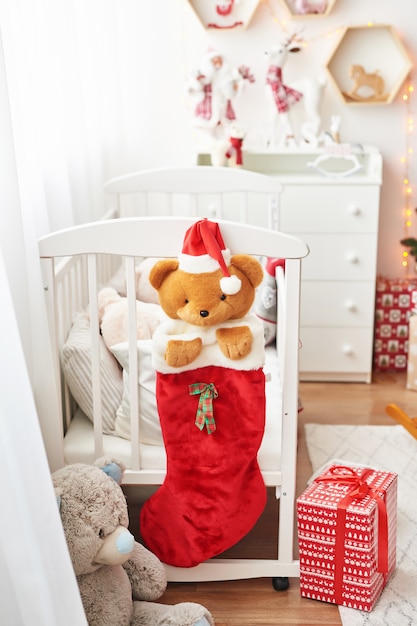 Crèche de Noël, salle de jeux pour enfants décorée pour le nouvel an, chambre d'enfants blanche, jouets et cadeaux de Noël dans la chambre d'enfants, lit blanc avec des peluches
