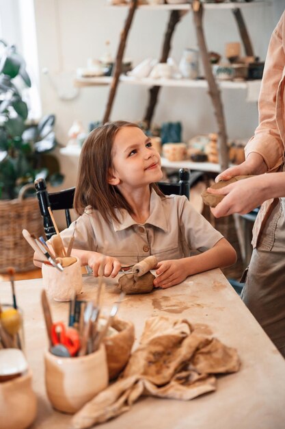 Photo créer la forme en utilisant de l'argile maman avec sa petite fille faisant de la poterie à la maison