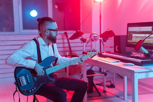 Créer de la musique et un concept de studio d'enregistrement - Un guitariste barbu enregistre une piste de guitare électrique