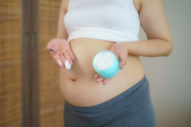 Crème blanche sur le gros ventre nu Prendre soin d'une peau parfaite et lisse pendant la grossesse