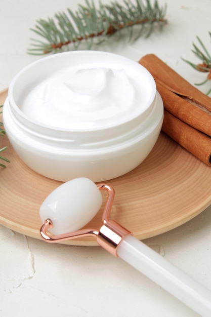 Crème blanche gua sha roller cannelle et sapin sur fond blanc