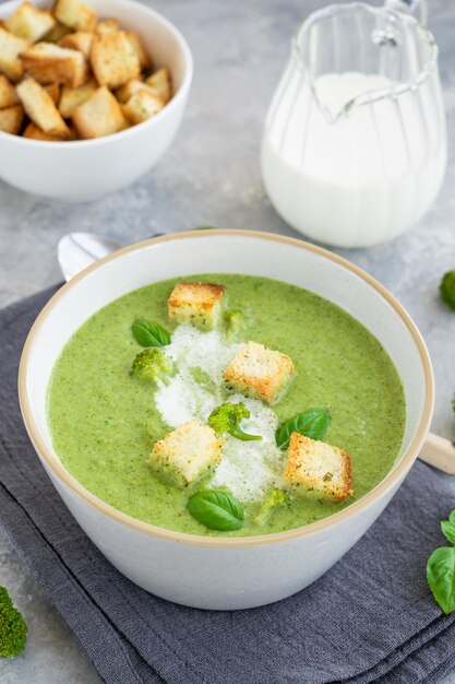 Crème de brocoli au basilic frais et croûtons dans un bol sur fond de béton gris