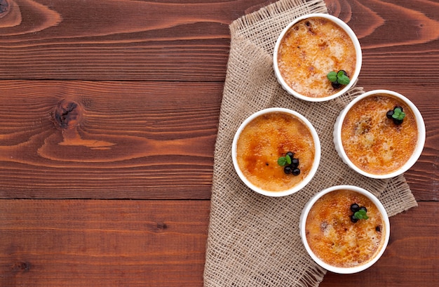 Crème brûlée dans un bol blanc avec croûte de sucre. Photographie en studio. style campagnard.