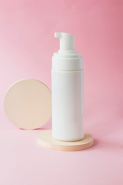 Photo crème cosmétique dans un tube sur fond rose. présentation de produits cosmétiques avec podium rond beige