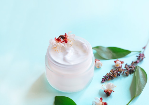 Crème cosmétique en pot et fleurs. Concept cosmétiques naturels, beauté, soins de la peau. Vue de dessus et espace de copie.