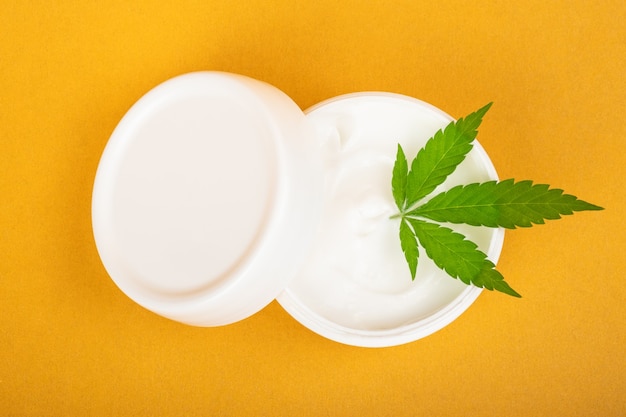 Crème cosmétique pour lutter contre les rides de la peau avec du cannabis sur fond jaune.