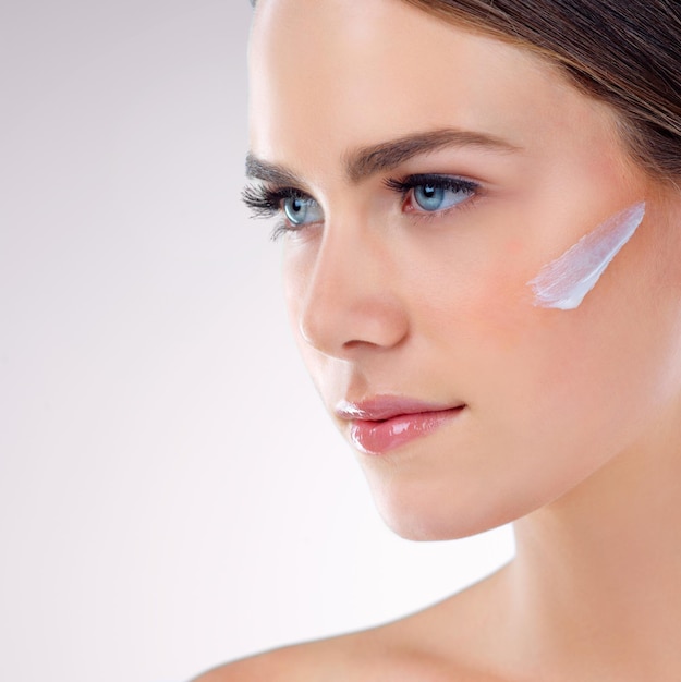 Crème faciale pensée ou modèle avec soin de la peau en studio sur fond blanc pour la fondation lueur ou lueur Lotion faciale fille modèle ou femme avec écran solaire idée de beauté ou produits cosmétiques résultats en gros plan