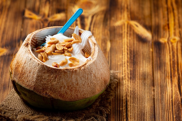 Photo crème glacée au lait de coco dans la coquille de noix de coco sur la surface en bois sombre