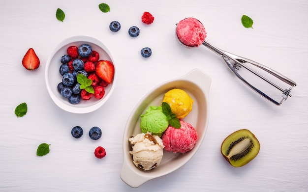 Crème glacée colorée avec baies mélangées et divers fruits mis en place sur fond blanc.
