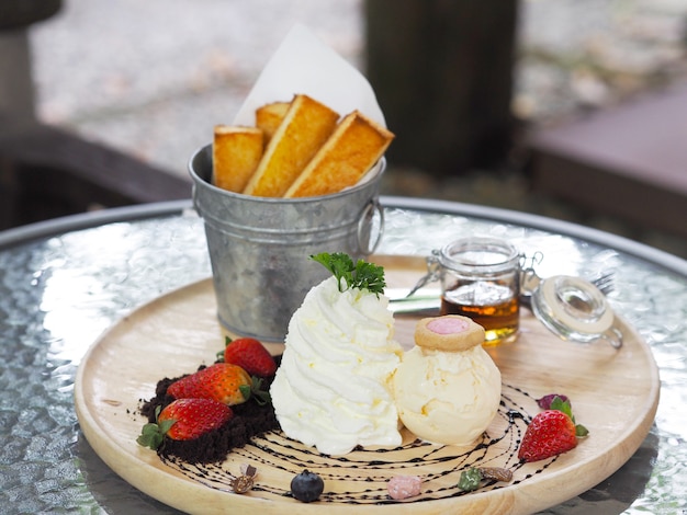 Crème glacée à la crème fouettée et aux fraises sur une plaque en bois.