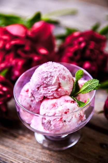 Crème glacée et fleur de pivoine comme symbole de l'été et des vacances sur fond de bois un