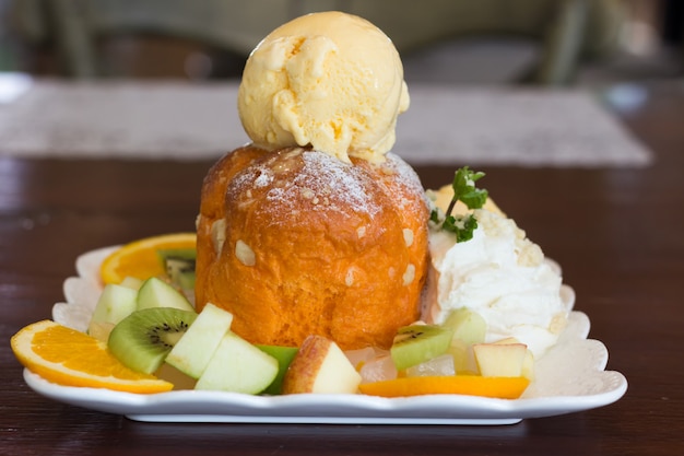 Crème glacée sucrée avec des fruits tranchés sur une table en bois, mélange de fruits et de la crème glacée