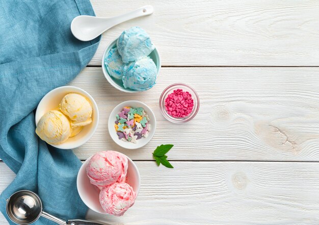 Crème glacée de trois types dans des tasses blanches sur un mur clair. Dessert d'été crémeux.