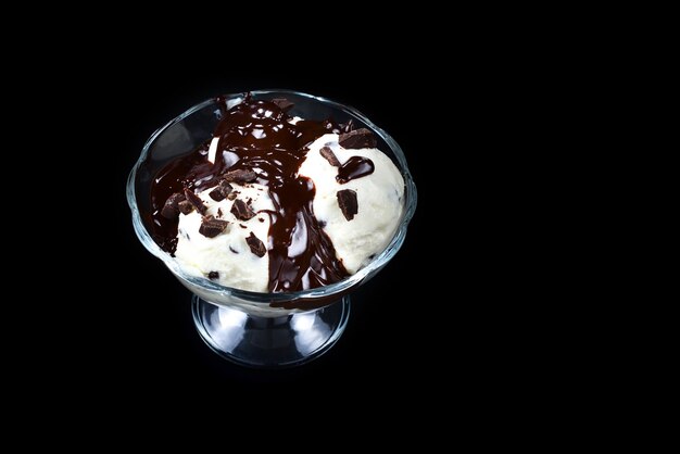 Crème glacée à la vanille dans un bol blanc avec du chocolat sur fond noir