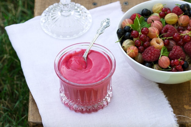 Crème de groseille rouge et une assiette aux fruits rouges sur un tabouret dans le jardin.