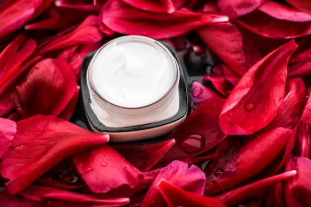 Crème hydratante pour soins de la peau sensible sur pétales de fleurs rouges et fond d'eau sciences naturelles pour la peau