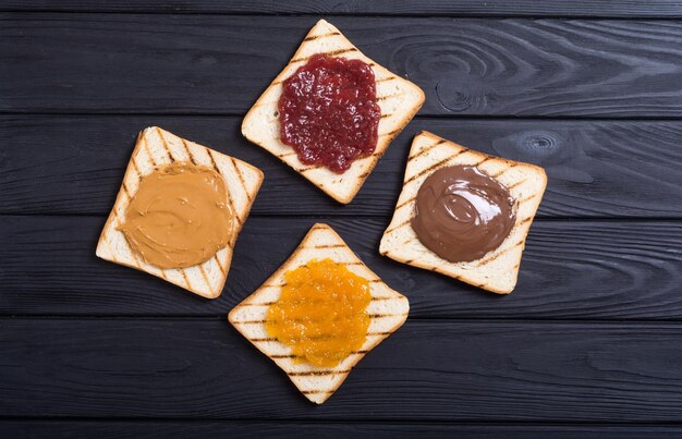 Photo crème de nougat aux noix avec confiture d'abricots au chocolat et aux fraises et sandwich au beurre de cacahuète