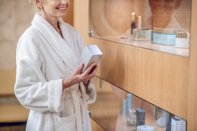 Crème pour le visage. Une femme en robe blanche choisissant une crème pour le visage dans un centre de beauté