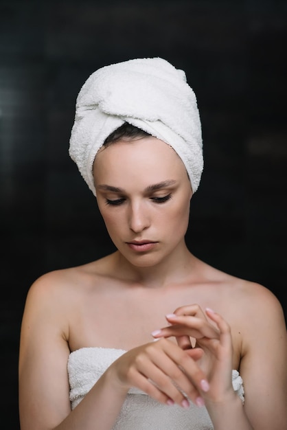 Photo crème pour le visage soins de la peau belle femme avec une serviette sur la tête après la douche cosmétologie