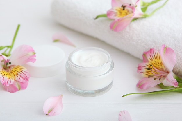 Crème de soin et fleurs sur les cosmétiques de table pour les soins de la peau