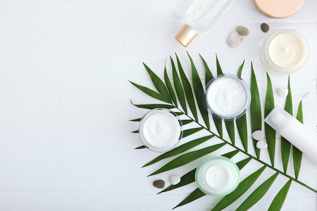 Crème de soin et fleurs sur fond coloré vue de dessus cosmétiques de soins de la peau