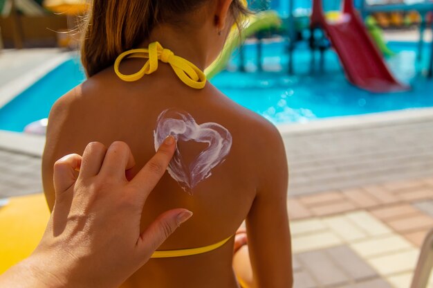 Crème solaire sur le dos de l'enfant. Mise au point sélective.