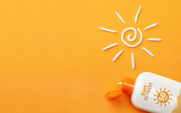 Photo crème solaire sur fond orange. flacon en plastique de protection solaire et crème en forme de soleil blanc.