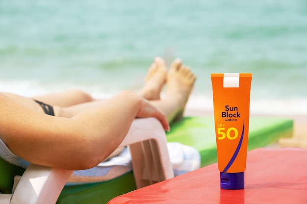 Crème solaire sur la plage au début de la femme à l'aide d'une bouteille de crème solaire lotion sur la plage