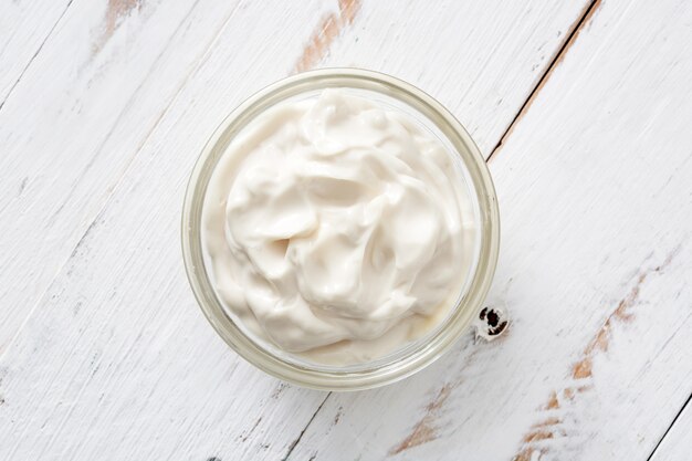 Crème sure dans un bol en cristal sur bois blanc