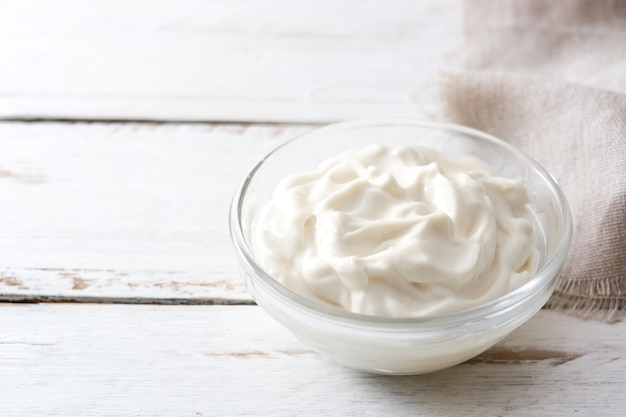 Crème sure dans un bol en cristal sur une table en bois blanc