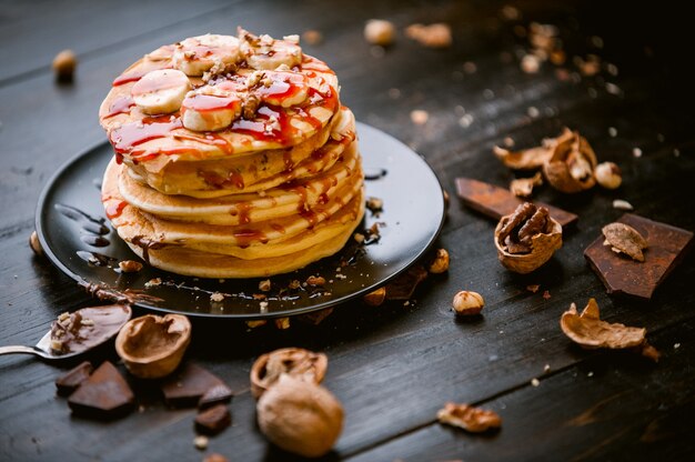 Crêpe au chocolat et pâte de noix, noix et banane sur une plaque noire