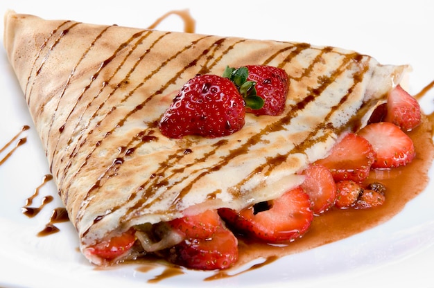 Crêpe aux fraises avec sirop de chocolat isolé sur plaque blanche