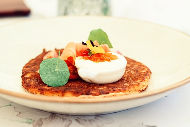 Crêpe de beignet de pommes de terre avec saumon caviar rouge et crème sure dans un restaurant de luxe à l'extérieur en été