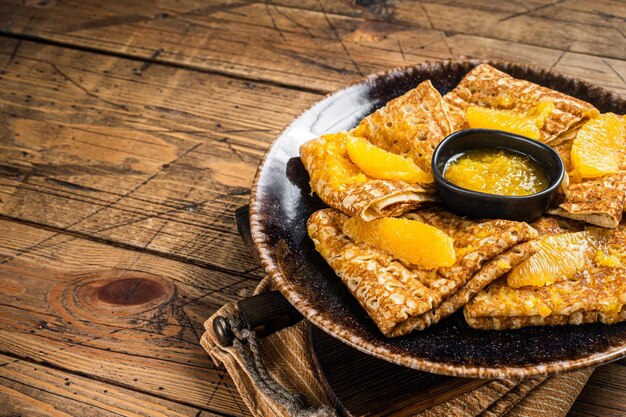 Crêpe française traditionnelle Suzette avec sauce à l'orange sur une assiette Fond en bois Vue de dessus Espace de copie