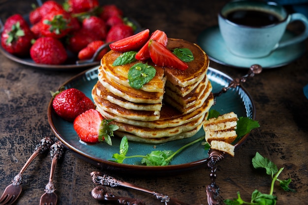 Crêpe petit-déjeuner américain classique avec du miel et des baies. Nature morte de crêpes luxuriantes, de miel et de fraises.