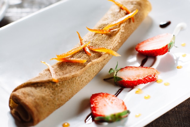 Crêpe roulée à la fraise sur plaque blanche