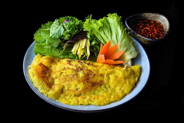 Crêpe vietnamienne aux fruits de mer sur fond noir vue latérale