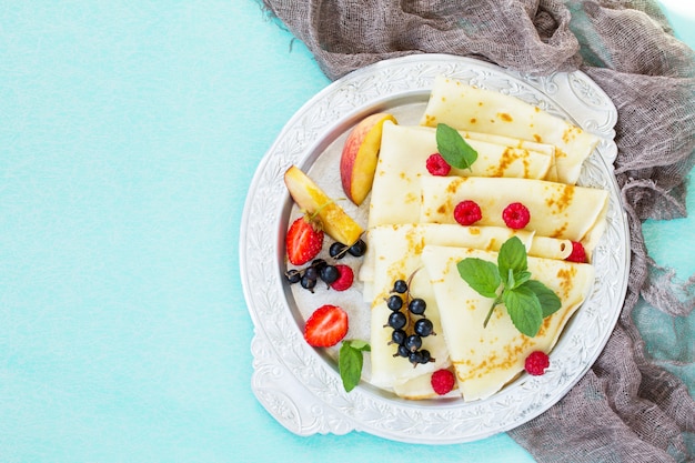 Crêpes sur une assiette avec du miel et des baies fraîches