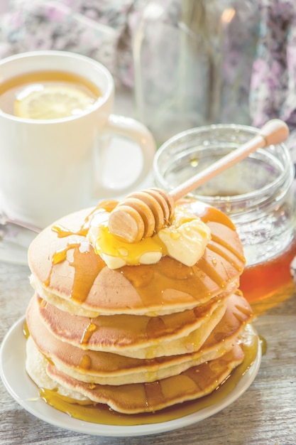 Crêpes au beurre et au miel et thé au citron pour le petit déjeuner. mise au point sélective.