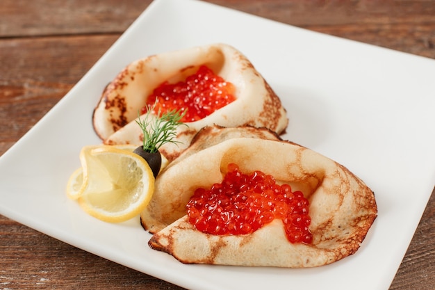 Crêpes au caviar rouge sur plaque blanche. Crêpes salées traditionnelles russes aux fruits de mer.