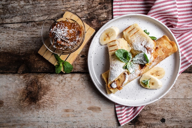 Crêpes au chocolat et banane, roulées sur plaque blanche