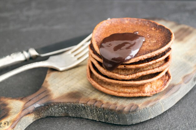 Crêpes au chocolat avec sauce au chocolat sur un fond sombre.